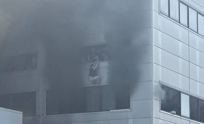 20일 오후 대전 대덕구 자동차 부품 공장에서 화재가 발생하자 건물 2층에 있던 직원들이 창문에 매달려 구조를 기다리고 있다. [사진 한서현씨]