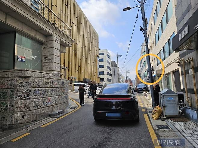 20일 오전 서울시 강남구 논현동 하이브 옛 사옥 건물의 지하 주차장 앞에 도로반사경이 설치되어 있지 않고 있다. 이날 BTS 성지 투어를 위해 건물을 방문한 글로벌 팬이 다가오는 차를 피하고 있다. /사진=박수빈 기자