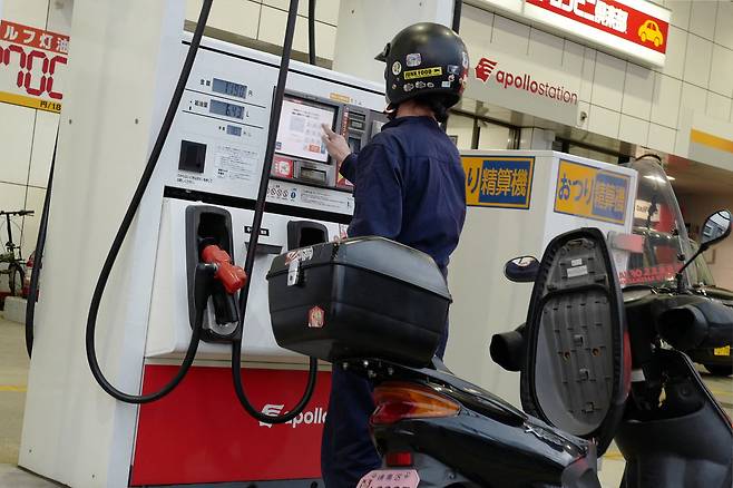 A man refuels a motorcycle at a gas station in Tokyo on March 18. Oil prices sank on March 18 after Iraq said it had resumed exports through Turkey, avoiding the effectively closed Strait of Hormuz, while equities rose following another tech-led advance on Wall Street. [AFP/YONHAP]
