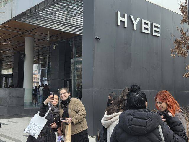 소속사 하이브 건물을 배경으로 사진 찍는 팬들.