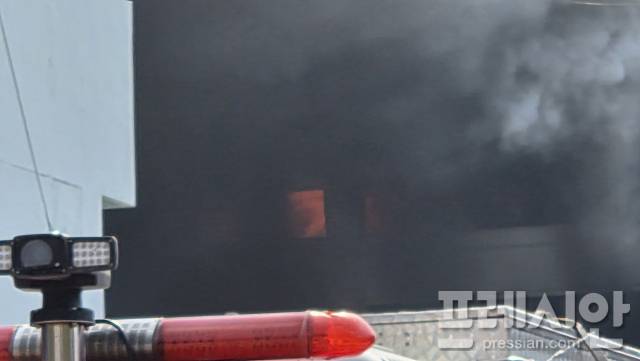 ▲소방차 경광등 뒤로 공장 내부에서 붉은 화염이 관측되고 있다 ⓒ프레시안(이재진)