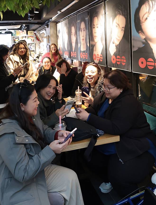 그룹 방탄소년단(BTS)의 광화문 공연을 앞둔 20일 서울 용산구 하이브 인근 카페에서 팬들이 멤버들의 뮤직비디오를 바라보며 행복한 시간을 보내고 있다. 뉴스1