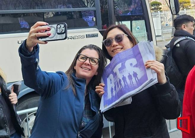 방탄소년단(BTS) 컴백 공연이 열리는 21일 서울 광화문 광장 일대에서 해외 팬들이 일부 일간지의 호외(특별판 신문)를 '굿즈'처럼 챙겨 기념사진을 찍고 있다. 박재현 기자