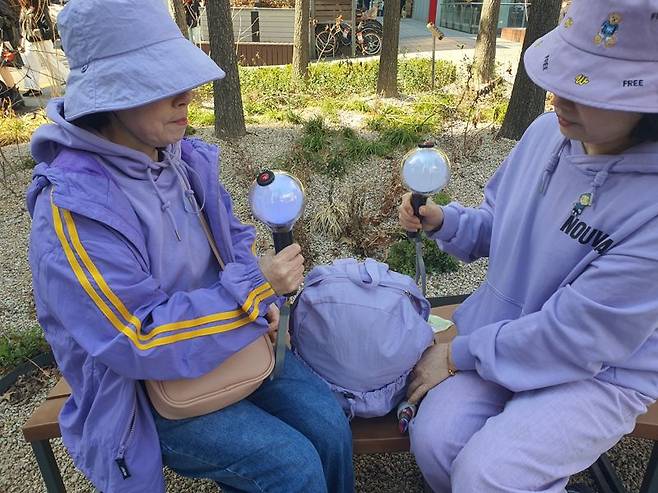 21일 서울 종로구 광화문 인근에서 BTS 상징색인 보라색 옷을 언니와 함께 맞춰 입고 나온 50대 이모씨가 BTS 응원봉을 들어보이고 있다. 사진=최승한 기자