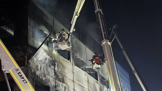 소방대원들이 인명 수색을 위해 고가사다리를 타고 화재 현장에 진입하고 있다.