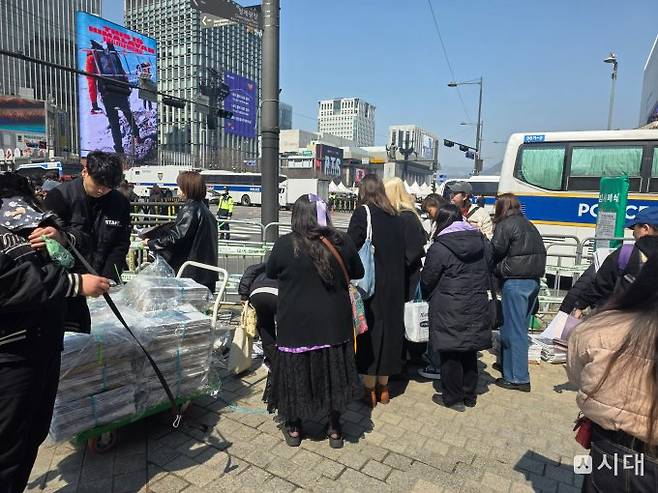 방탄소년단 완전체 컴백 공연을 앞둔 21일 오후 서울 광화문 광장 인근에서 주요 언론사가 호외로 제작한 BTS 특별판을 팬과 시민에게 배포하고 있다. / 사진=김성아 기자