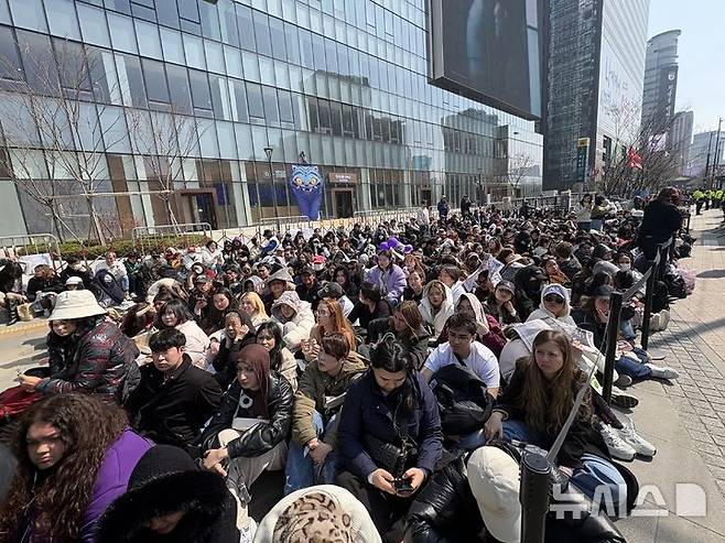 [서울=뉴시스]신유림 기자=21일 서울 종로구 광화문광장 KT빌딩 인근 '명당존'에 관람객들이 5~6열로 빽빽하게 앉아 공연을 기다리고 있다. 2026.03.21.spicy@newsis.com