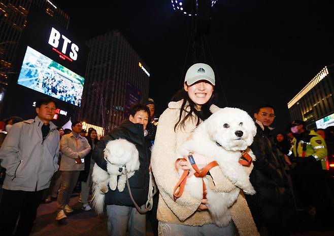 방탄소년단(BTS) 광화문 컴백 공연이 열린 21일 서울 종로구 광화문 광장에서 한 시민과 강아지와 함께 공연을 관람하기 위해 이동하고 있다.