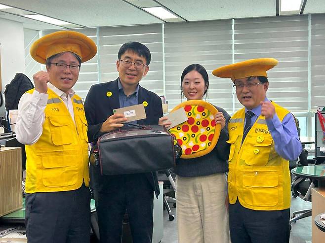 김성환(오른쪽 첫번째) 기후에너지환경부 장관이 지난 17일 제4호 행복전도사에 선정된 신동혁 대기환경정책과 사무관에게 행복피자를 전달한 후 기념촬영을 하고 있다. [기후에너지환경부 제공]