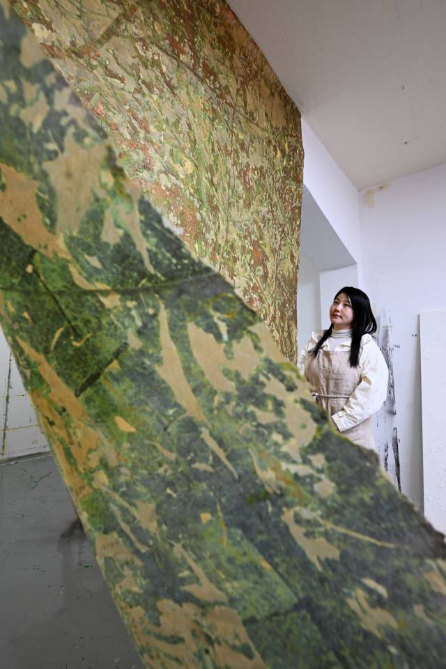 조현수 화가가 작업실에서 닥종이에 입힌 동박이 부식되며 만들어지는 작품을 선보이고 있다. 조명 위치와 종이 배열에 따라 앞면(오른쪽)과 뒷면의 이미지가 다르게 드러난다.