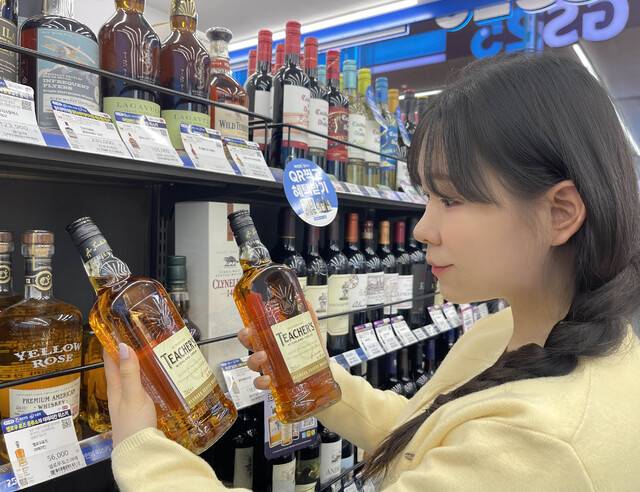 GS25가 단독 판매하는 스카치 위스키 ‘티처스’가 SNS와 온라인 커뮤니티에서 하이볼용 가성비 위스키로 화제를 모으며 완판 행진을 이어가고 있는 가운데, 이달 13일 3차 물량을 선보였다. 사진은 GS25 매장에서 모델이 가성비 위스키 티처스를 살펴보고 있다.(GS25 제공)