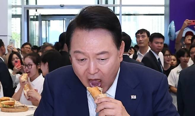 윤석열 전 대통령이 2023년 6월22일 베트남 하노이 국가컨벤션센터에서 열린 한-베트남 파트너십 박람회 중 K-푸드 박람회를 방문해 김치로 만든 반미 샌드위치를 맛보고 있다. 연합뉴스