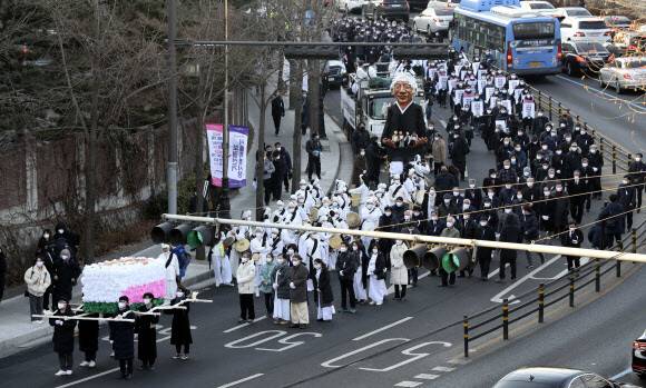 2021년 2월19일 오전 서울 종로구 서울대학교병원 장례식장에서 출발한 고 백기완 통일문제연구소장의 운구행렬이 노제가 열리는 대학로에 들어서고 있다. 장례위는 백 소장이 생전 민족문화에 남다른 관심을 가졌던 만큼 꽃상여와 대나무 깃대가 달린 만장, 각종 상징물 등을 사용해 전통 장례 절차를 재현하는 노제를 지냈다. 연합뉴스