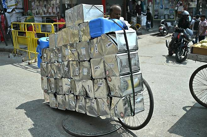 지난 13일(현지시간) 인도 벵갈루루의 거리에서 한 남성이 자전거에 빈 기름통을 싣고 이동하고 있다. AFP연합뉴스