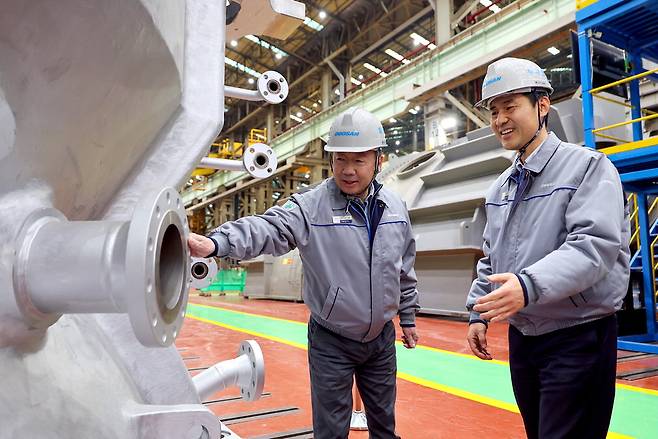 박정원 두산그룹 회장(왼쪽)이 지난달 11일 경남 창원 두산에너빌리티 사업장을 방문해 제작 중인 발전용 가스터빈 제품을 살펴보고 있다.  두산그룹