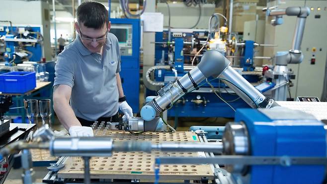 덴마크 유니버설로봇(UR) 제품인 협동로봇으로 작업하는 근로자.  유니버설로봇