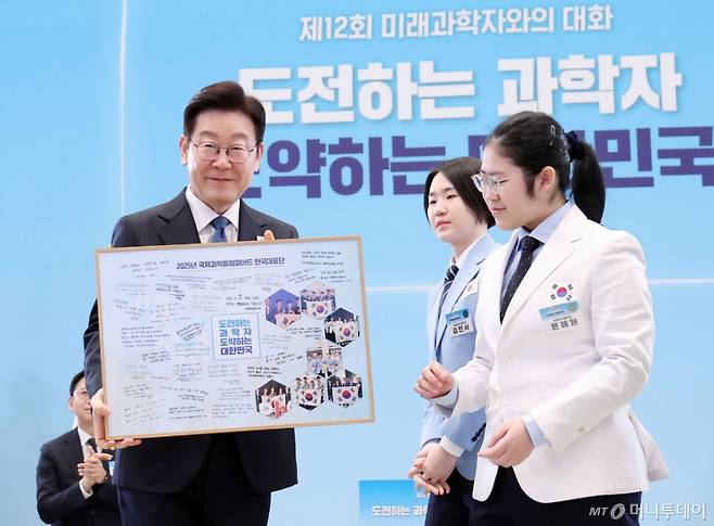 이재명 대통령이 지난달 청와대에서 열린 대통령과학장학생·올림피아드 대표단 친수 및 간담회(미래 과학자와의 대화)에서 국제과학올림피아드 대표단에게 우리나라 도약을 이끌 미래 과학자로서 다짐을 담은 기념액자 전달을 받고 있다. /사진=뉴시스