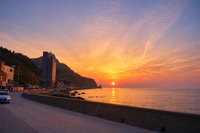 24일 울릉군 사동리 해안가에서 바라본 라마다 바이 윈덤 울릉 호텔 너머로 일출이 장관을 이루고 있다. 공식 오픈을 앞둔 이 호텔은 최근 대규모 정규직 채용에 나서 지역 청년 고용 시장에 새로운 활력을 불어넣고 있다. /황진영 기자