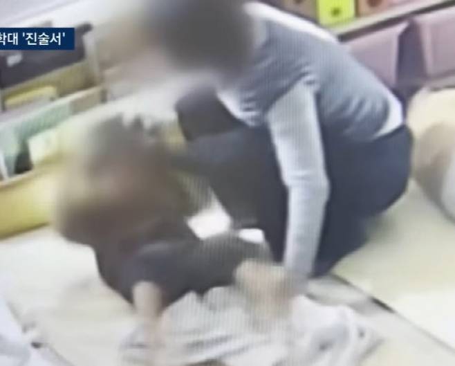 국회 어린이집 교사가 아동 머리채를 잡고 일으키고 있다. (사진=JTBC 캡처)