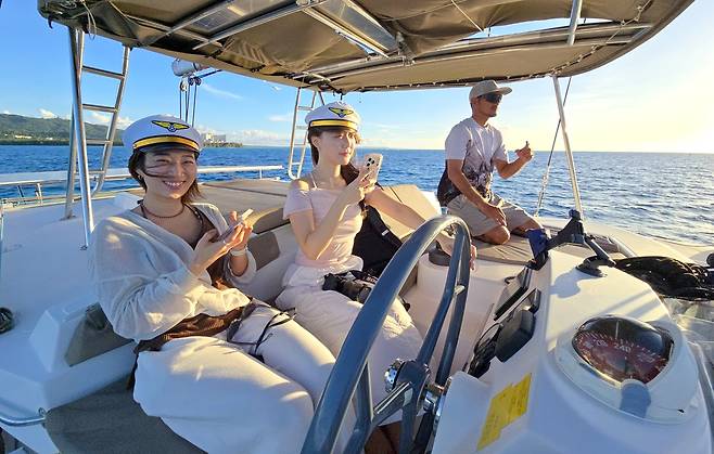 한국 여행자들이 마나가하 요트유람선에서 선장흉내를 내보고 있다.