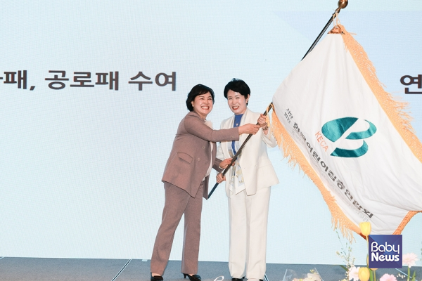 임진숙 한국어린이집총연합회 신임 회장과 김경숙 전임 회장이 제14대·15대 회장 이취임식에서 대회기를 흔들고 있다. ⓒ한국어린이집총연합회
