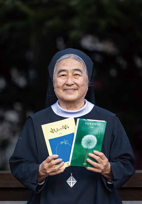 이해인 수녀가 1976년 출간한 첫 시집 <민들레의 영토>와 지난해 11월 출간한 산문집 <민들레 솜털처럼>을 들고 환하게 웃고 있다.