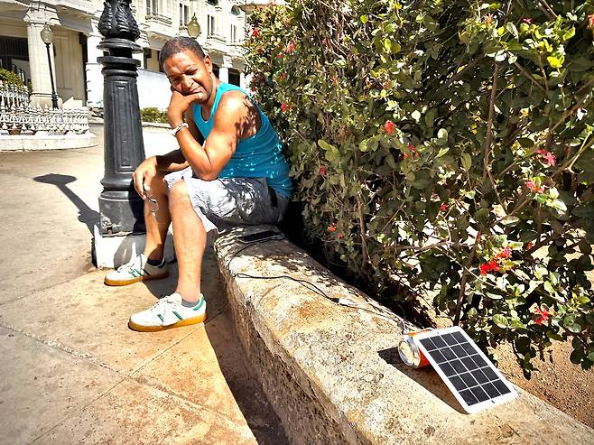지난 22일 국가 정전 사태 다음 날, 아바나 시내에서 한 쿠바인이 작은 태양광 패널로 휴대전화를 충전하고 있다. /박국희 특파원