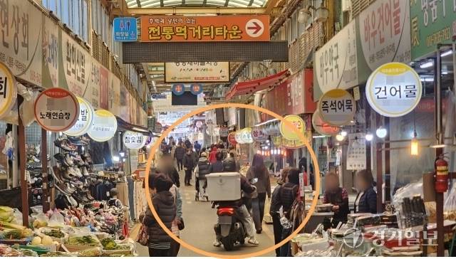 광명시 광명동 새마을시장에서 이용객들이 주행하는 오토바이를 피해 상점 매대쪽으로 걷고 있다. 한준호기자