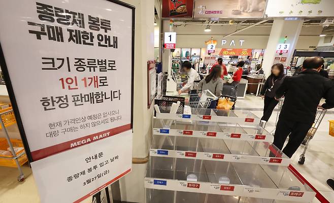 미국·이스라엘과 이란 간 전쟁 여파로 나프타 공급이 불안정한 가운데 종량제봉투 등 비닐류 품절 사례가 잇따르는 등 비닐 대란 우려가 확산하고 있다. 26일 부산 동래구 메가마트에 구매제한 안내문 옆 봉투 판매대가 텅 비어 있다. [연합]