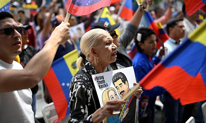 베네수엘라 카라카스 시민들이 축출된 대통령 니콜라스 마두로와 그의 부인 실리아 플로레스의 심리가 미국 뉴욕 남부연방법원에서 열린 26일(현지시간) 이들을 지지하는 집회를 열고 있다. 카라카스=로이터연합뉴스