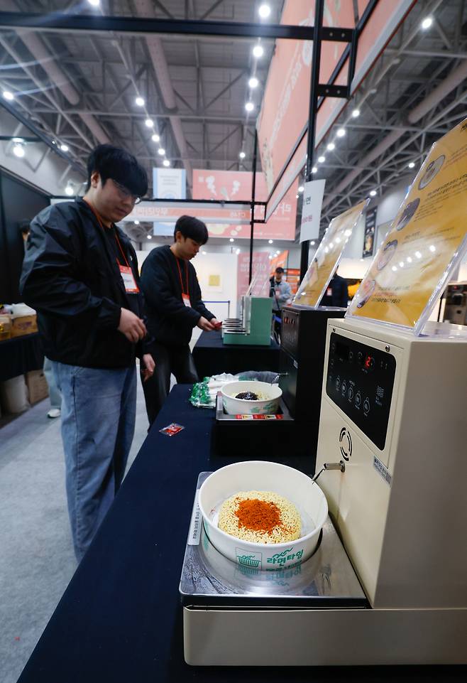 27일 인천 연수구 송도컨벤시아에서 열린 ‘2026 대한민국 라면박람회’에서 관계자들이 셀프라면 기기를 시연하고 있다.