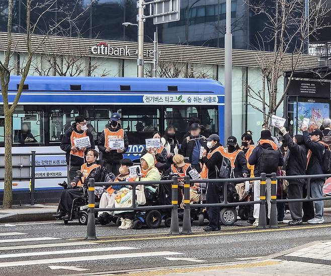 전국장애인차별철폐연대(전장연) 회원들이 3월27일 출근길 서울 종로구 광화문 버스 승강장에서 '탑승 시위'를 벌이고 있다. ⓒ 연합뉴스