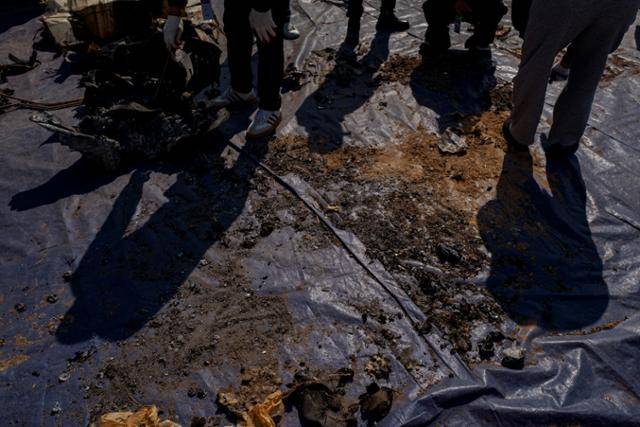 3월 13일 진행된 기체 잔해물 재조사 현장에서 유족들이 작은 뼛조각 하나라도 놓칠세라 방수포 바닥에 흩어진 잔해와 흙먼지를 샅샅이 살피고 있다. 무안=하상윤 기자