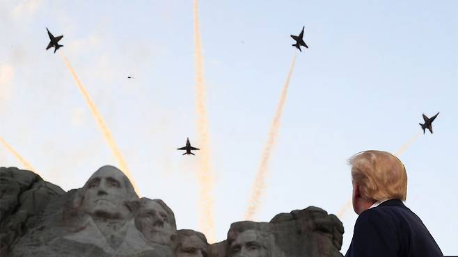 지난 2020년 7월 3일, 도널드 트럼프 미국 대통령이 사우스다코타주 러시모어산에서 열린 독립기념일 행사에서 워싱턴·제퍼슨·루스벨트·링컨 대통령 조각상 위로 날아가는 전투기의 비행을 보고 있습니다.(로이터)