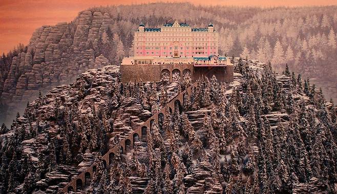2014년 개봉한 웨스 앤더슨(Wes Anderson) 감독의 ‘그랜드 부다페스트 호텔’(The Grand Budapest Hotel)은 가상의 유럽 국가를 배경으로 한 호텔과 그곳을 둘러싼 인물들의 이야기를 그리며 1930년대를 중심으로 한 시공간을 축으로, 한 시대의 종말과 그 이후를 관통하는 변화를 다층적으로 포착한다. 호텔 지배인이었던 구스타브와 로비 보이 제로의 관계를 중심으로 서사가 전개되지만, 이는 개인의 일대기에 머물지 않고, 질서와 품위로 상징되던 세계가 해체되어가는 흐름을 함께 비춘다. [영화 스틸샷]