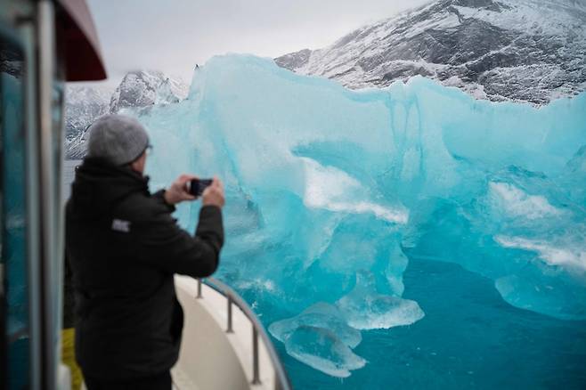 ▲지난달 15일 그린란드 카피실리트 마을 인근 빙하 만에서 한 관광객이 보트에서 빙산을 촬영하고 있다. 지구 온난화로 전 세계 빙하는 빠르게 녹고 있고, 해수면은 상승하고 있다. (사진= AFP/연합뉴스)