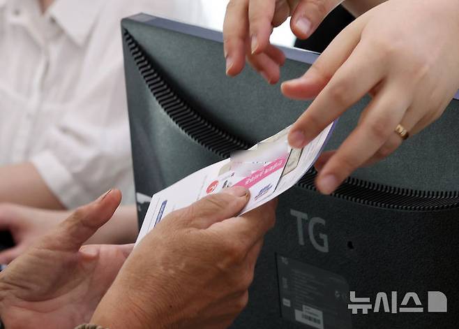 [부산=뉴시스] 하경민 기자 = 민생회복 2차 소비쿠폰 신청 첫날이었던 지난해 9월22일 부산 부산진구 가야2동주민센터에서 시민들이 지원금을 받고 있다. 2025.09.22. yulnetphoto@newsis.com