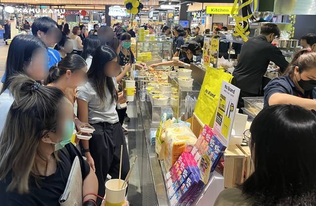 이마트가 방콕의 랜드마크 쇼핑몰 ‘센트럴 방나’에 오픈한 노브랜드 1호점 내에 위치한 한국 키친 코너에 태국 고객들이 주문 설명을 읽어보고 있다.(이마트 제공)