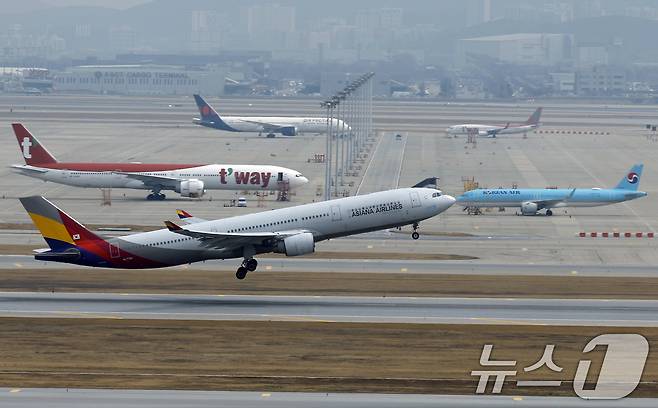 인천국제공항 계류장에 대기하는 항공기 앞으로 아시아나항공 항공기가 이륙하고 있다. ⓒ 뉴스1 박정호 기자
