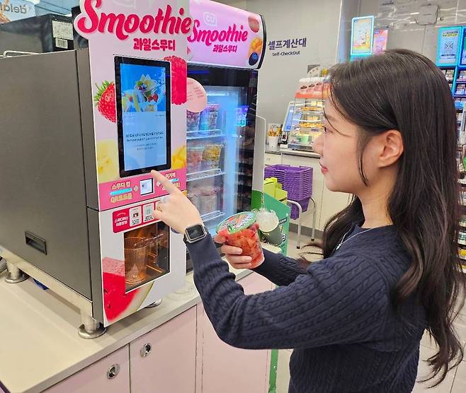 편의점 CU 홍보 모델이 스무디 전용 컵과일을 스무디 기계에 올리고 있다. 이 기계는 스무디 전용 기기로 컵과일을 1분 만에 시원한 스무디로 만든다. CU 제공