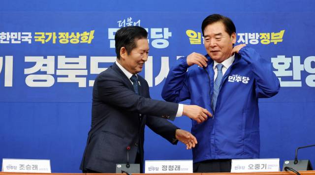 더불어민주당 정청래 대표가 지난 1일 국회에서 열린 오중기 경북도지사 후보 환영식에서 오 후보에게 당 점퍼를 입혀주고 있다. 연합뉴스