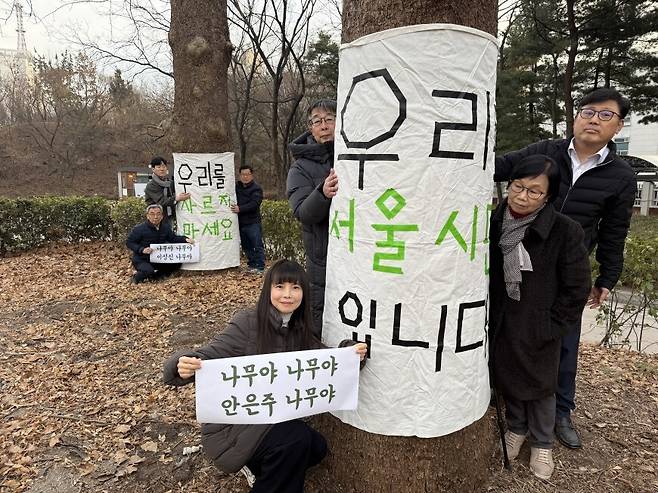 2026년 2월26일 서울 종로구 경희궁 서쪽, 환경보건시민센터 회원들이 벌목 예정인 플라타너스 옆에서 펼침막을 들고 있다. 환경보건시민센터 제공
