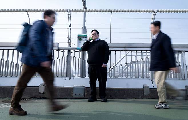 SOS생명의전화를 주도한 박성민씨가 지난달 27일 서울 마포대교 위에서 전화기를 귀에 대고 있다. 자식처럼 챙기던 전화는 15살이 됐지만, 여전히 자살 위험에 놓인 많은 이들이 필요로 하고 있다. 장진영 기자