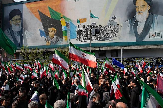 현지시간 1일 이란 테헤란에서 시민들이 이란 이슬람 혁명수비대 해군 사령관 알리레자 탕시리와 지난 3월 말 이스라엘의 공습으로 숨진 다른 희생자들의 장례 행렬에 참여하며 이란 국기를 들고 있다. AP=연합뉴스