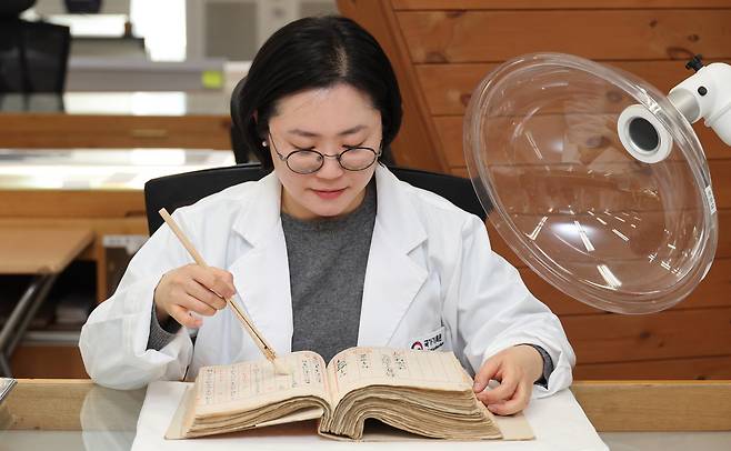 조은혜&nbsp;국가기록원 복원관리과 학예연구사가 지난 3월25일 경기 성남시 국가기록원 성남분원에서 1909년 대한제국 시절 작성된 판결문인 ‘형사재판 원본’&nbsp;기록물 표면의 오염 물질을 붓으로 없애는 건식 클리닝을 시연하고 있다. 사진 오른쪽 장비는 집진기 일종인 국소 배기 장치다. 성남=이제원 선임기자