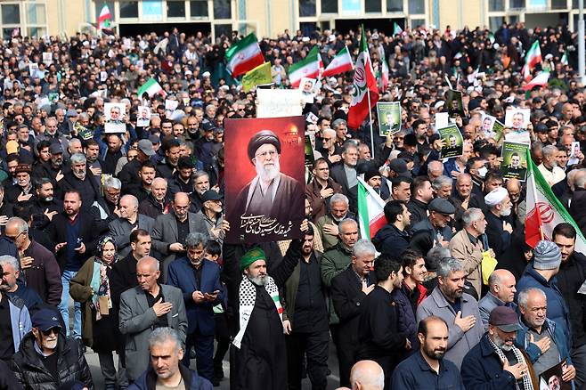 21일(현지 시간) 이란 테헤란에서 전 이란 혁명수비대(IRGC) 대변인 알리 모하마드 나이니의 장례식이 거행된 가운데 한 이란 남성이 고(故) 이란 최고 지도자 아야톨라 알리 하메네이의 사진을 들고 있다. EPA연합뉴스