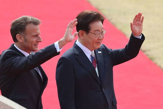 3일 서울 청와대에서 열린 공식 환영식에 참석한 에마뉘엘 마크롱 프랑스 대통령(왼쪽)이 이재명 대통령과 함께 손을 흔들고 있다. AFP 연합뉴스