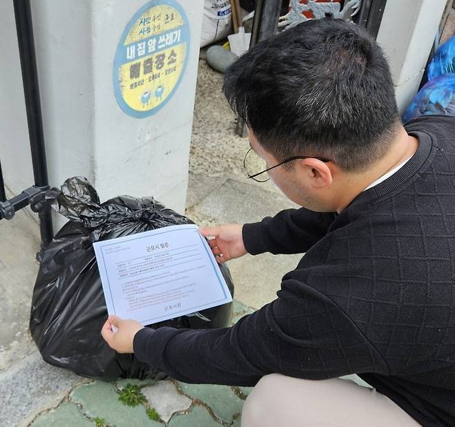 일반 봉투에 쓰레기 배출 신고 표지를 부착하는 모습. 경기 군포시 제공