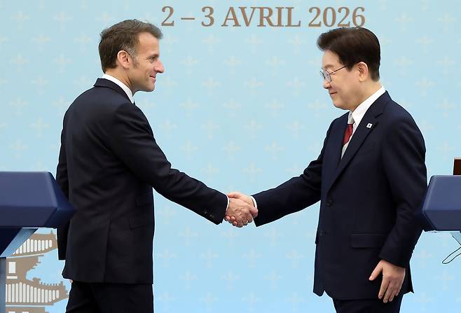 President Lee Jae Myung and French President Emmanuel Macron shake hands after a joint press conference at Cheong Wa Dae in Seoul on Friday. (Yonhap)