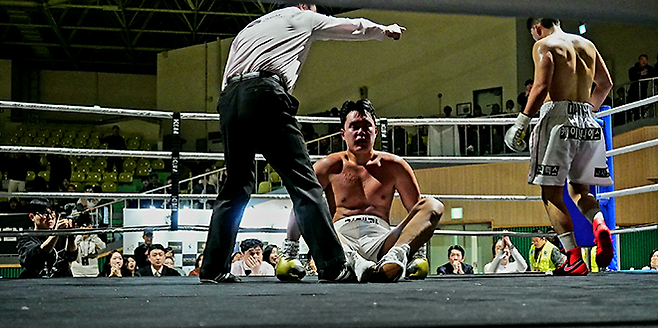 사단법인 한국복싱커미션 헤비급 챔피언 김태광이 2026년 3월 서울과학기술대학교 체육관 특설 링에서 타이틀 1차 방어전을 치르다 3라운드 도전자한테 다운을 허용하여 주저앉아 있다. 사진=KBM